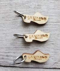 wood cut wooden shoe closed stitch marker with the GarenHuis Logo on it